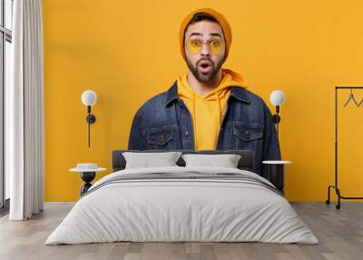 Shocked young hipster guy in fashion jeans denim clothes posing isolated on yellow orange background studio portrait. People sincere emotions lifestyle concept. Mock up copy space. Keeping mouth open. Wall mural