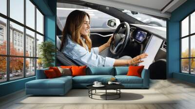 Side profile view caucasian happy smiling confident satisfied woman drive hold put hand on steering wheel look at maps on tablet sitting in auto new car automobile Journey traveling lifestyle concept. Wall mural