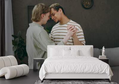 Side profile view fun young couple two gay men wear casual clothes dance together near window sofa couch at home flat rest spend free spare time in living room Pride day june month love lgbtq concept Wall mural