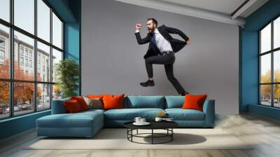 Side view of crazy young business man in classic suit shirt tie posing isolated on grey background. Achievement career wealth business concept. Mock up copy space. Jumping, running, fooling around. Wall mural