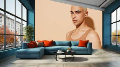 Side view young trendy serious blond latin hispanic gay man 20s with make up in beige tank shirt looking camera isolated on plain light ocher background studio portrait People lgbt lifestyle concept. Wall mural