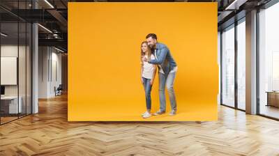 Smiling bearded man in casual clothes have fun with child baby girl. Father little kid daughter isolated on yellow background. Love family parenthood childhood concept. Pointing index finger aside. Wall mural