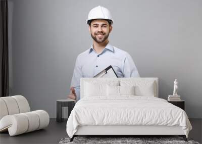 Smiling business man in light shirt, protective construction white helmet isolated on grey background. Achievement career wealth business concept. Hold clipboard with papers document showing thumb up. Wall mural