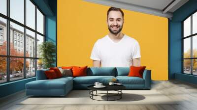 Smiling handsome young bearded man guy in white casual t-shirt posing isolated on yellow wall background studio portrait. People sincere emotions lifestyle concept. Mock up copy space. Looking camera. Wall mural