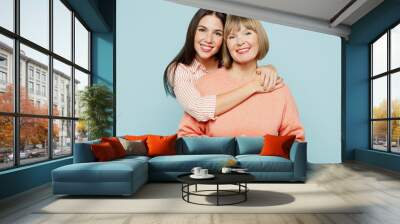 Smiling lovely fun satisfied elder parent mom with young adult daughter two women together wearing casual clothes hugging cuddle look camera isolated on plain blue cyan background Family day concept Wall mural