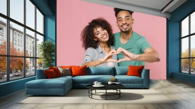 Smiling young african american couple two friends guy girl in gray green casual clothes showing shape heart with hands, heart-shape sign isolated on pastel pink color wall background studio portrait. Wall mural