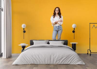 Smiling young brunette business woman in white shirt glasses isolated on yellow wall background studio portrait. Achievement career wealth business concept. Mock up copy space. Holding hands crossed. Wall mural