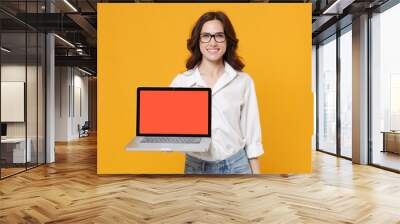 Smiling young business woman in white shirt glasses isolated on yellow wall background. Achievement career wealth business concept. Mock up copy space. Hold laptop pc computer with blank empty screen. Wall mural