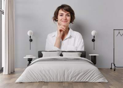 Smiling young business woman in white shirt posing isolated on grey background studio portrait. Achievement career wealth business concept. Mock up copy space. Put hand prop up on chin looking camera. Wall mural