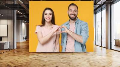 Smiling young couple two friends guy girl in pastel blue casual clothes isolated on yellow background. People lifestyle concept. Mock up copy space. Showing shape heart with hands, heart-shape sign. Wall mural