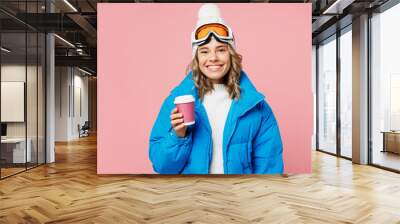 Snowboarder woman wear blue suit goggles mask hat ski padded jacket hold takeaway paper cup coffee to go isolated on plain pastel pink background Winter extreme sport hobby weekend trip relax concept Wall mural