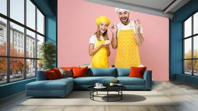 Teen happy girl dad father chef cook confectioner baker in yellow apron cap at table hold muffin macaroons dessert isolated on pastel pink background Mousse cake food workshop master class process Wall mural