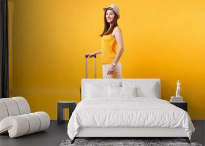 Traveler tourist woman in summer casual clothes, hat with suitcase isolated on yellow orange background. Female passenger traveling abroad to travel on weekends getaway. Air flight journey concept. Wall mural