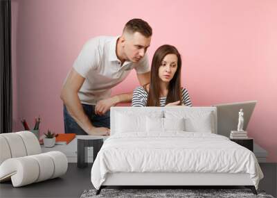 Two young concentrated business woman man colleagues sit work at white desk with contemporary laptop isolated on pastel pink background. Achievement career concept. Copy space advertising, co working. Wall mural