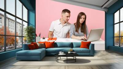 Two young concentrated business woman man colleagues sit work at white desk with contemporary laptop isolated on pastel pink background. Achievement career concept. Copy space advertising, co working. Wall mural