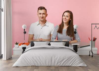 Two young smiling business woman man colleagues sit work at white desk with contemporary laptop isolated on pastel pink background. Achievement career concept. Copy space advertising, youth co working Wall mural