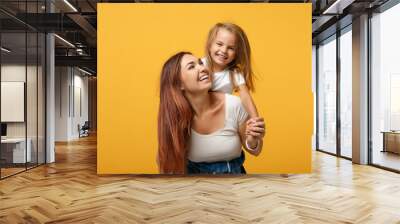 Woman in light clothes have fun with cute child baby girl 4-5 years old. Mommy little kid daughter isolated on yellow background studio portrait. Mother's Day love family parenthood childhood concept. Wall mural