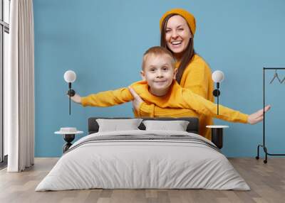 Woman in yellow clothes have fun posing with cute child baby boy 4-5 years old. Mommy little kid son isolated on blue background studio portrait. Mother's Day love family parenthood childhood concept. Wall mural