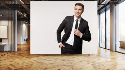 Young confident employee business corporate lawyer man 20s in classic formal black grey suit shirt tie work in office keeping hands in pockets look aside isolated on white background studio portrait Wall mural