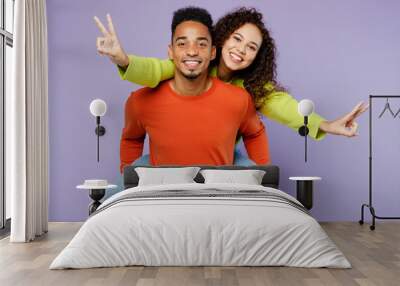 Young cool couple two friends family man woman of African American ethnicity wear casual clothes together giving piggyback ride to joyful, sit on back isolated on pastel plain light purple background. Wall mural