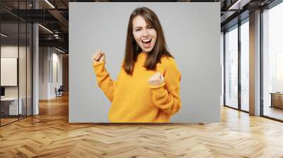 Young excited happy overjoyed attractive beautiful woman in casual knitted yellow sweater do winner gesture clench fist say yes isolated on grey background studio portrait People lifestyle concept Wall mural