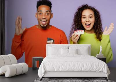 Young exultant happy cheerful couple two friends family man woman of African American ethnicity wear casual clothes together hold donut spread hands isolated on pastel plain light purple background. Wall mural