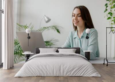 Young friendly smiling happy successful employee business woman in casual blue shirt sit work at workplace white desk with laptop pc computer at light modern office indoor. Achievement career concept Wall mural