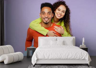 Young fun couple two friends family man woman of African American ethnicity wear casual clothes together giving piggyback ride to joyful, sit on back isolated on pastel plain light purple background. Wall mural