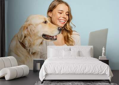 Young fun owner IT woman with her best friend retriever dog wear casual clothes hold use work on laptop pc computer isolated on plain pastel light blue background studio. Take care about pet concept. Wall mural