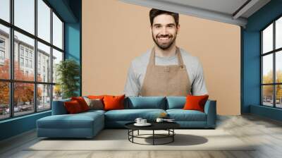 Young fun smiling happy caucasian man barista barman employee wear brown apron work in coffee shop looking camera isolated on plain pastel light beige background studio Small business startup concept Wall mural