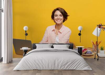 Young fun successful employee IT business woman wear casual shirt sit work at office desk using laptop pc computer typing document isolated on plain yellow color background Achievement career concept Wall mural