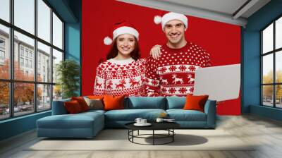 Young happy fun couple friends two man woman in sweater hat hold use work on laptop pc computer isolated on plain red background studio. Happy New Year 2022 celebration merry ho x-mas holiday concept. Wall mural