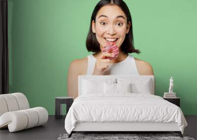 Young happy fun woman wearing white clothes hold in hand two donuts dessert looking camera isolated on plain pastel light green background. Proper nutrition healthy fast food unhealthy choice concept. Wall mural