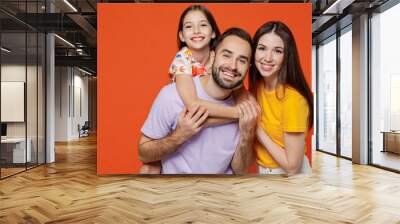 Young happy parents mom dad with child kid daughter teen girl wear basic t-shirts giving piggyback to daughter isolated on yellow background studio portrait. Family day parenthood childhood concept Wall mural