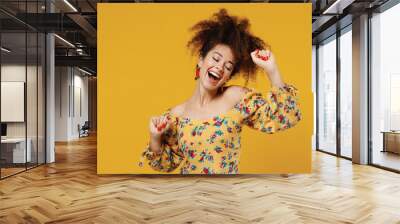 Young happy satisfied beautiful caucasian woman 20s with culry hair in casual clothes dancing have fun at party close eyes isolated on plain yellow background studio portrait People lifestyle concept. Wall mural