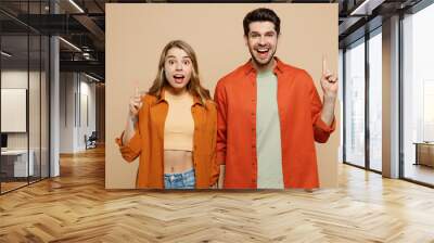 Young insighted smart proactive couple two friends family man woman wear casual clothes hold index finger up with great new idea together isolated on pastel plain light beige color background studio. Wall mural