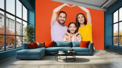 Young parents mom dad with child kid daughter teen girl in basic t-shirts hold hands above head showing shape heart with hands heart-shape sign isolated on yellow background studio Family day concept Wall mural