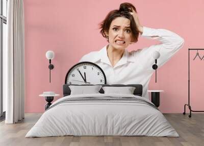 Young sad displeased employee business secretary woman corporate lawyer in classic formal white shirt work in office hold clock spread hands isolated on pastel pink color background studio portrait. Wall mural