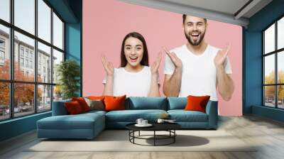 Young shocked surprised happy couple two friends bearded man brunette woman in white basic blank print design t-shirts spreading hands say wow isolated on pastel pink color background studio portrait. Wall mural