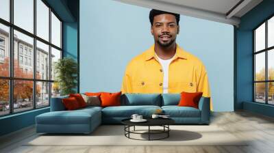 Young smiling handsome attractive happy man of African American ethnicity 20s wearing yellow shirt look camera isolated on plain pastel light blue background studio portrait. People lifestyle concept. Wall mural