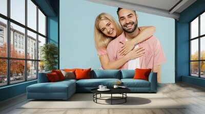 Young smiling happy cheerful couple two friends family man woman in casual clothes looking camera hug together isolated on pastel plain light blue background studio portrait People lifestyle concept. Wall mural