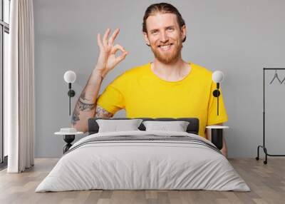 Young smiling happy cheerful fun cool Caucasian man he wearing yellow t-shirt casual clothes look camera showing okay ok gesture isolated on plain grey background studio portrait. Lifestyle concept. Wall mural