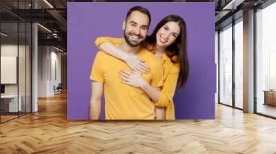 Young smiling happy cheerful nice lovely couple two friends family man woman 20s together wearing yellow casual clothes looking camera hud cuddle isolated on plain violet background studio portrait Wall mural