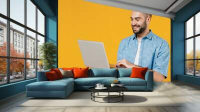 Young smiling happy freelancer copywriter satisfied caucasian man 20s wear blue shirt hold use work on laptop pc computer isolated on plain yellow background studio portrait. People lifestyle concept. Wall mural