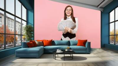 Young smiling successful business woman in glasses holding bundle lots of dollars, cash money isolated on pink background. Lady boss. Achievement career wealth concept. Copy space for advertisement. Wall mural