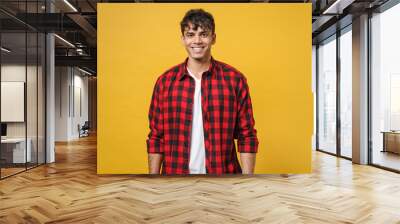 Young spanish latinos attractive handsome smiling cheerful stylish fashionable student man 20s wear red checkered shirt, white t-shirt look camera isolated on yellow color background studio portrait. Wall mural