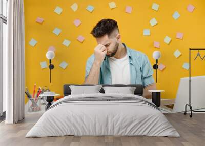 Young tired exhausted troubled pensive employee business man in shirt sit work at white office desk with pc laptop keep eyes closed rub put hand on nose isolated on yellow background studio portrait. Wall mural