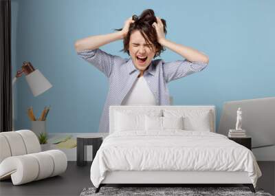 Young troubled stressed employee business woman 20s in casual shirt sit work at white office desk with pc laptop hold sctratch head screaming shout isolated on pastel blue background studio portrait Wall mural