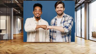 Young two friends cheerful cool smiling men 20s wear white casual shirts looking camera together give fistbump isolated plain dark royal navy blue background studio portrait. People lifestyle concept. Wall mural