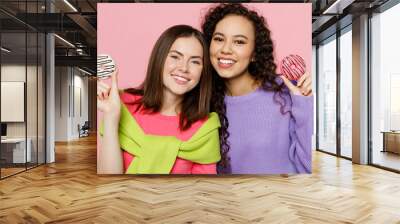 Young two friends happy joyful fun women 20s wears green purple shirts together eat sweet donuts snack cover mouth eye look camera isolated on pastel plain light pink color background studio portrait. Wall mural